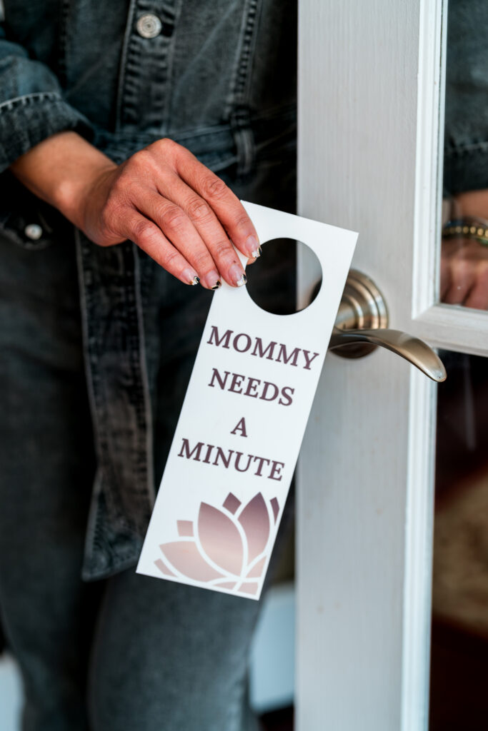 The 'Mommy Needs A Minute' door hanger in use, signaling a moment of peace for moms, photographed for Mom-Care Oasis